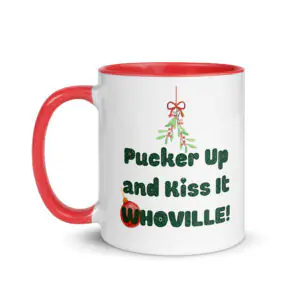White ceramic Christmas coffee mug with a red handle and interior, featuring mistletoe graphics, a red ornament, and green text reading "Pucker Up and Kiss It Whoville!" on the side.