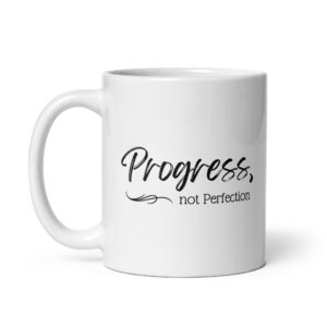 White glossy ceramic recovery coffee mug printed with black cursive script reading Progress, not Perfection and an elegant decorative swirl underline.