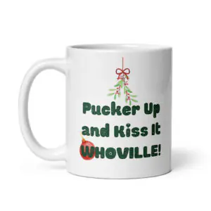 All-white ceramic Christmas coffee mug featuring mistletoe graphics, a red ornament, and green text reading "Pucker Up and Kiss It Whoville!" printed on the side.